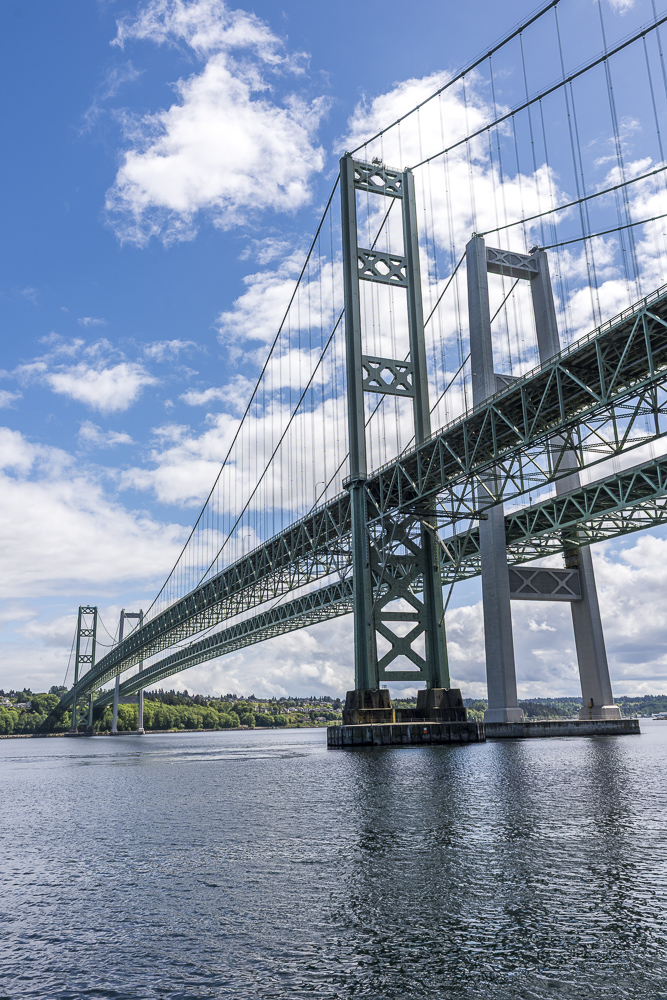 A view of the Tacoma Narrows Bridges from the water surface.  The bridges span "The Narrows" a geographical part of the Puget Sound.  The 2 bridges are a portion of Hiway 16 that that spans the Tacoma Narrows strait of Puget Sound between Tacoma and the Kitsap Peninsula.  The 2 bridges replaced the original "Galloping Gertie" which collapsed into the water during a wind storm November 7, 1940.