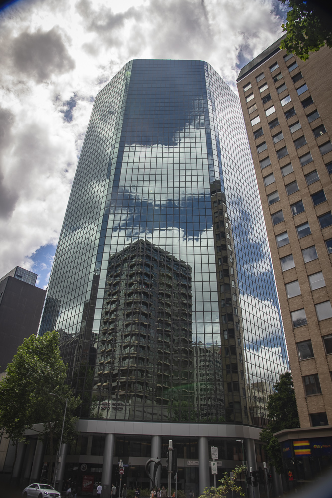 Reflections off the glass surfaces of the skyscraper, clouds, sky and surrounding buildings in downtown Melbourne, Australia.