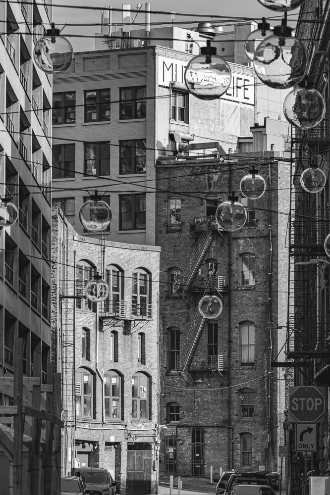 A Black and White looking through clear light globes and old brick buildings on Post Ave. in Seattle, Washington