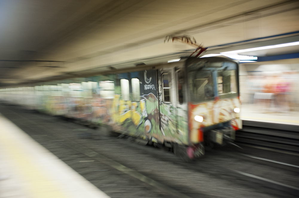 A passing subway covered in colorful graffiti in Rome, Italy