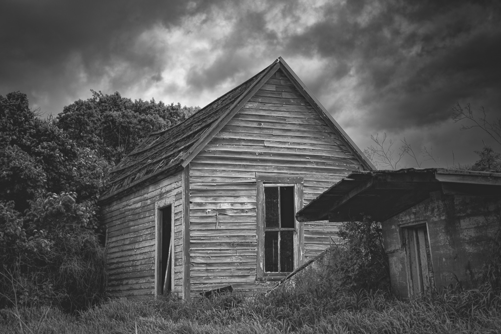 A black and White image of a spooky old abandoned house under threatening weather clouds in Eastern Washington