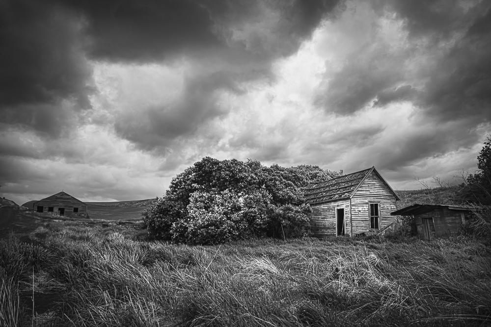 A black and White image of a spooky old abandoned house under threatening weather clouds in Eastern Washington