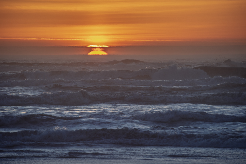 Sunset over the waves at Cape Disappointment, Washington.  The atmospheric inversion causes the sun to appear in several locationas at once.  This is effect is also known as Feta Morgana.