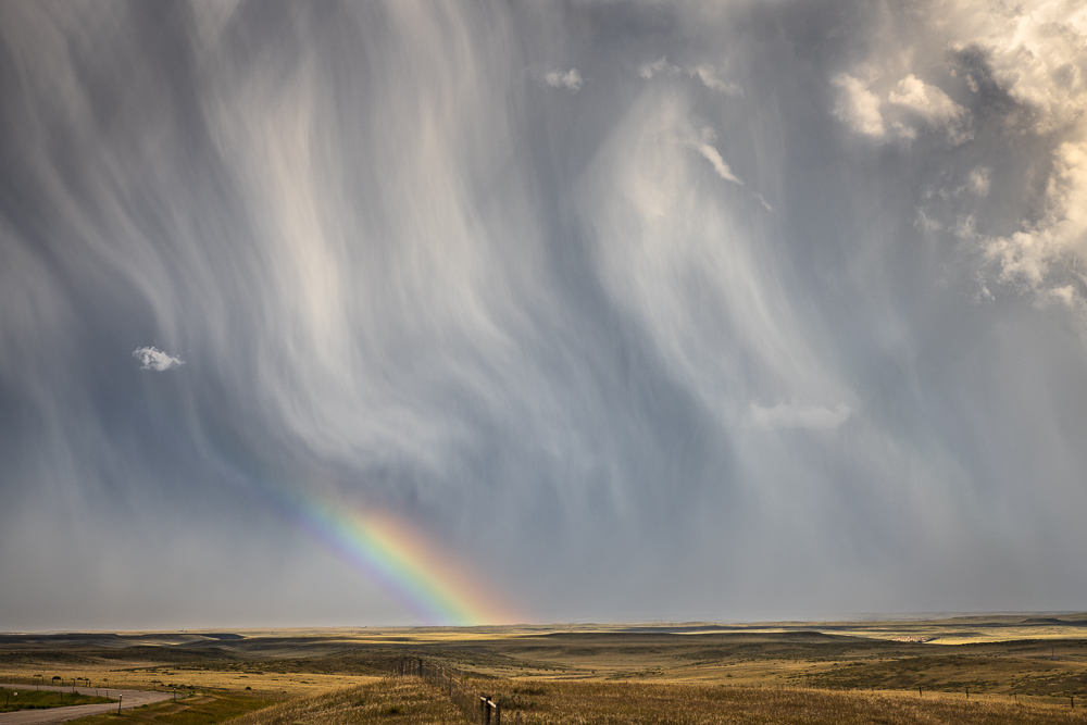 A major trextured storm cloud unloading rain and hail but sharing a wonderful rainbow near Chugwater, Wyoming