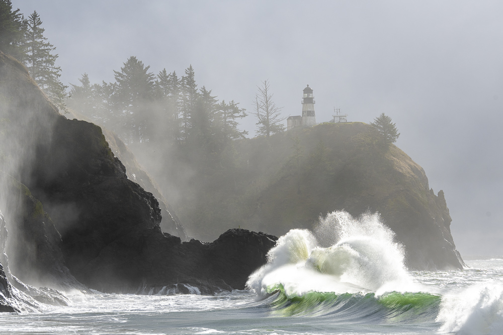 Morning fog enhances the dramatic beauty of the waves crashing into the cliffs at Cape Disappointment Lighthouse at the mouth of the Columbia River in Southwest Washington