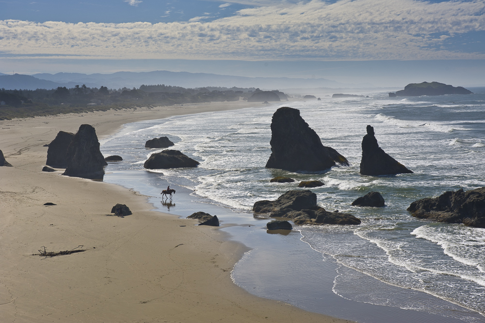 A woman takes a quiet, horse ride on a solitary beazach in the Oregon National Wildlife Refuge in Bandon, Oregon