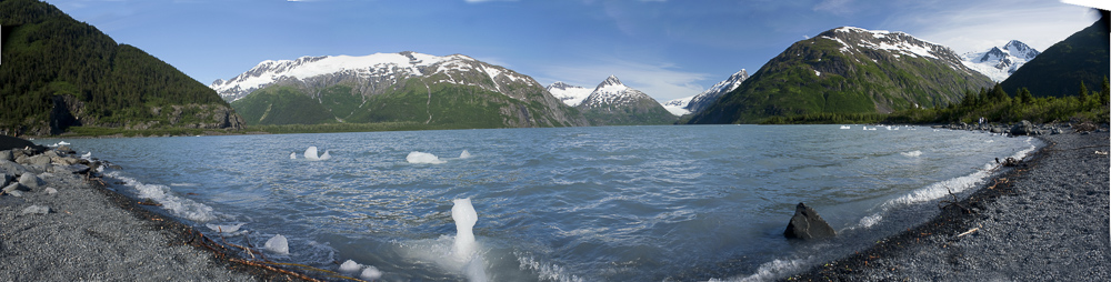A summertime panoramic view of Portage Lake, Alaska. Little icebergs, and  surrounding Kenai Mountains and glaciers.